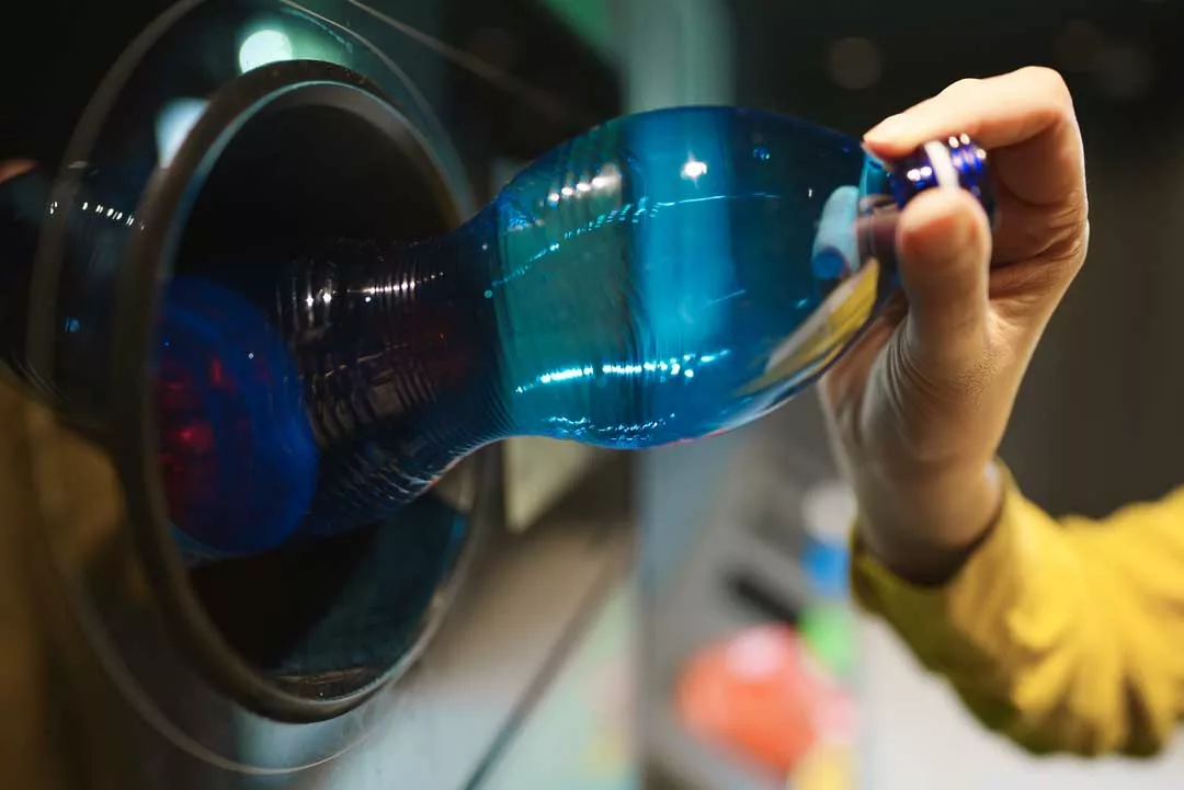 Frau legt Pfandflasche in Rückgabeautomat