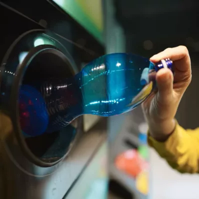 Frau legt Pfandflasche in Rückgabeautomat